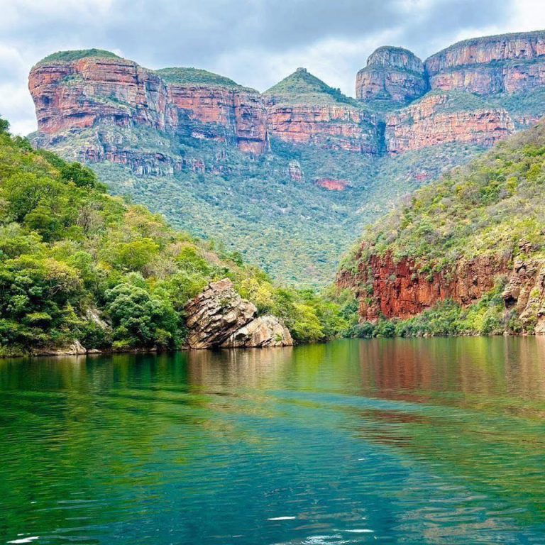 Rooi sandsteenkranse en groen water in die Blyderivier-canyon